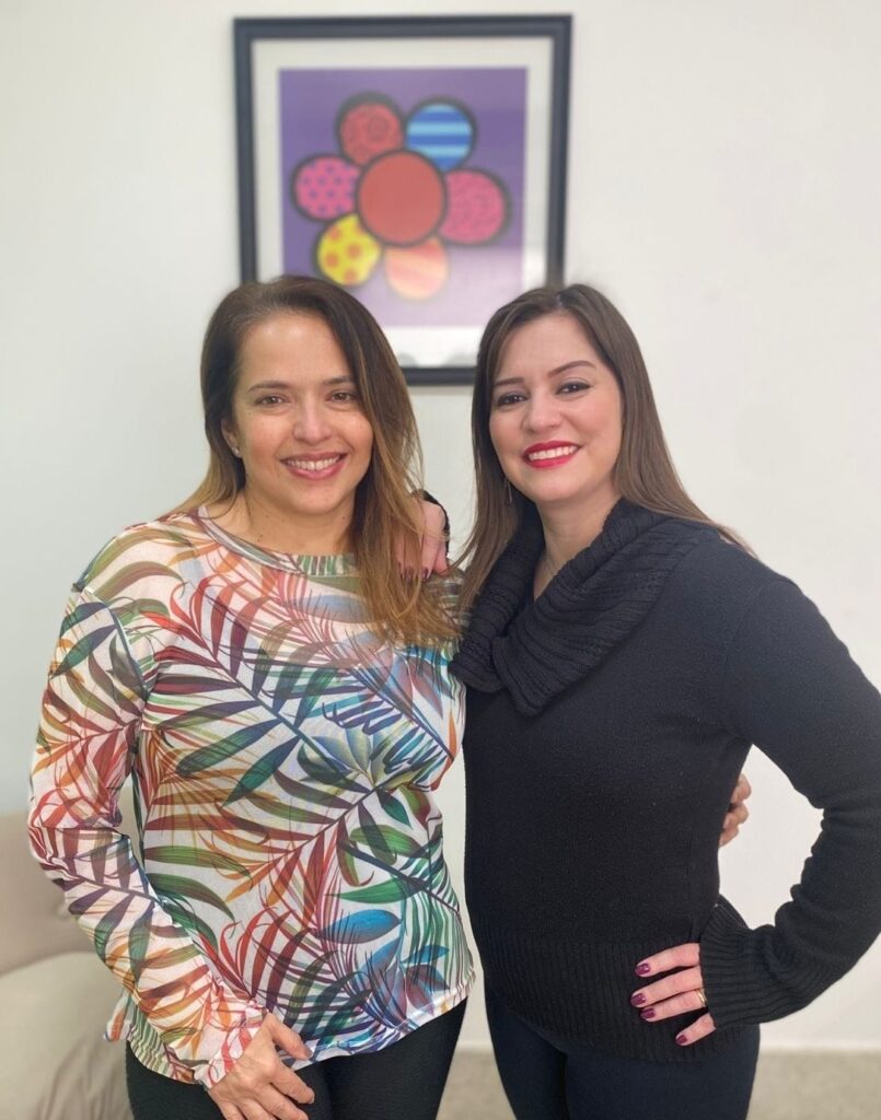 Psicopedagoga e Psicóloga com quadro ao fundo